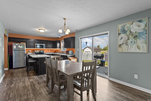 384 Ariel Dr, Kokomo, IN 46901 - dining area featuring a chandelier, dark wood-type flooring, and baseboards