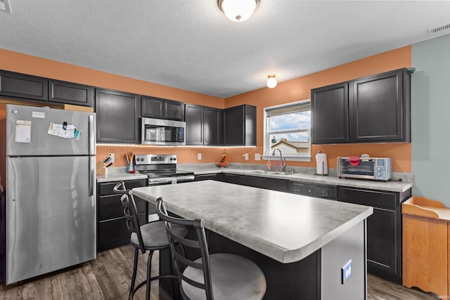 384 Ariel Dr, Kokomo, IN 46901 - kitchen featuring appliances with stainless steel finishes, a sink, wood finished floors, a center island, and light countertops