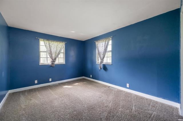 carpeted empty room with plenty of natural light and baseboards