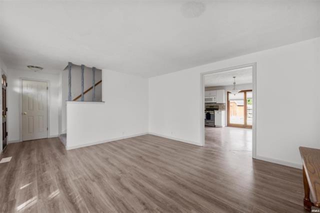 unfurnished living room featuring wood finished floors and baseboards