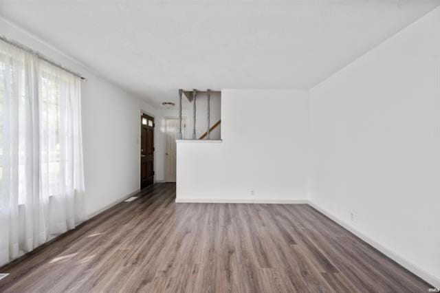 unfurnished living room with wood finished floors, stairs, and baseboards