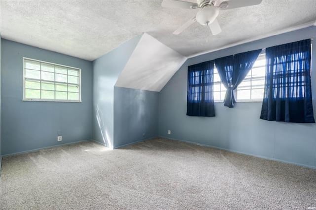 bonus room featuring plenty of natural light, a textured ceiling, carpet floors, a ceiling fan, and vaulted ceiling