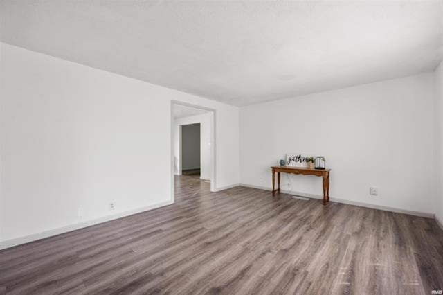 spare room featuring wood finished floors and baseboards