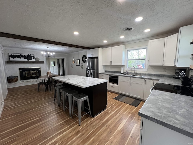 18065 Buzzard Roost Rd, Magnet, IN 47520 - kitchen with freestanding refrigerator, a sink, a textured ceiling, light wood-type flooring, and a kitchen bar