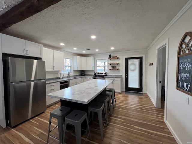 18065 Buzzard Roost Rd, Magnet, IN 47520 - kitchen with appliances with stainless steel finishes, a kitchen bar, a sink, dark wood-style flooring, and ornamental molding