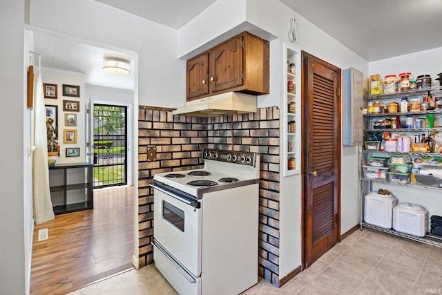 kitchen with electric range, under cabinet range hood, light tile patterned floors, and ornamental molding