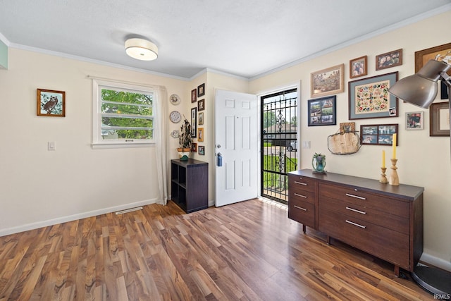 entrance foyer with dark wood-style floors, ornamental molding, and baseboards