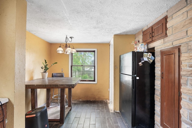 kitchen with freestanding refrigerator, dark wood-style floors, a textured ceiling, a chandelier, and brown cabinetry