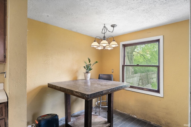 dining room featuring a chandelier, a textured wall, and a textured ceiling
