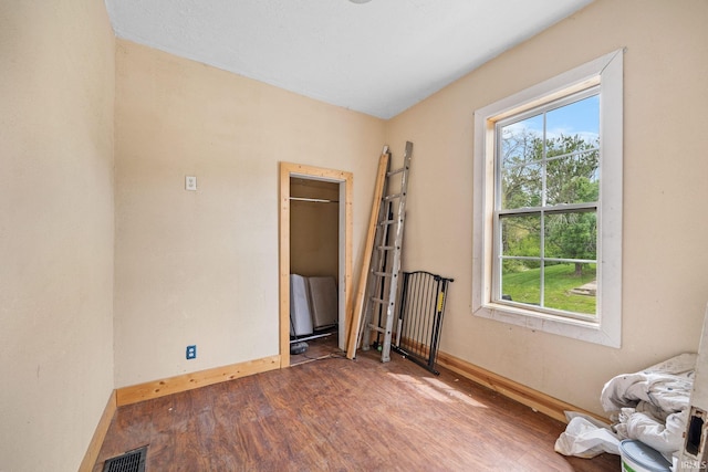 spare room featuring plenty of natural light, wood finished floors, and baseboards