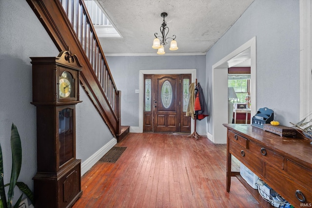 foyer entrance featuring a chandelier, stairs, hardwood / wood-style flooring, baseboards, and a textured ceiling