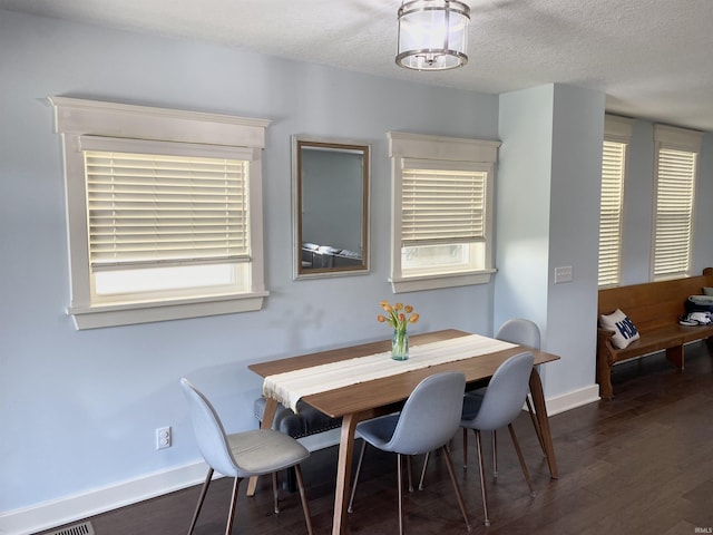 dining space featuring wood finished floors, baseboards, and a textured ceiling