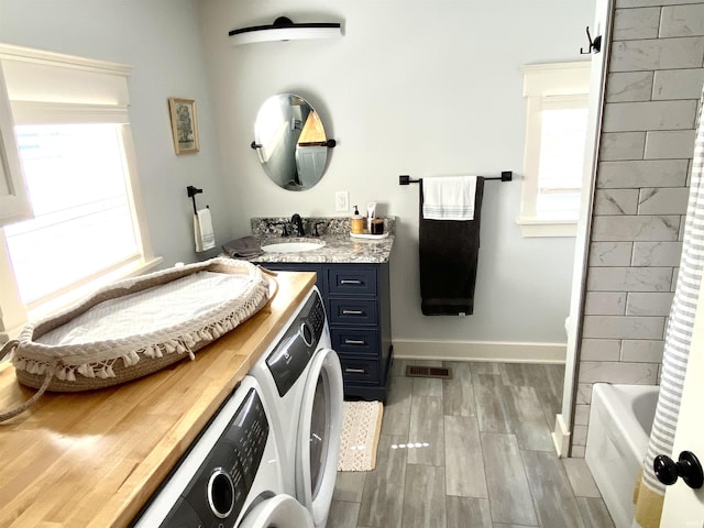full bath featuring washing machine and clothes dryer, healthy amount of natural light, wood finished floors, and vanity