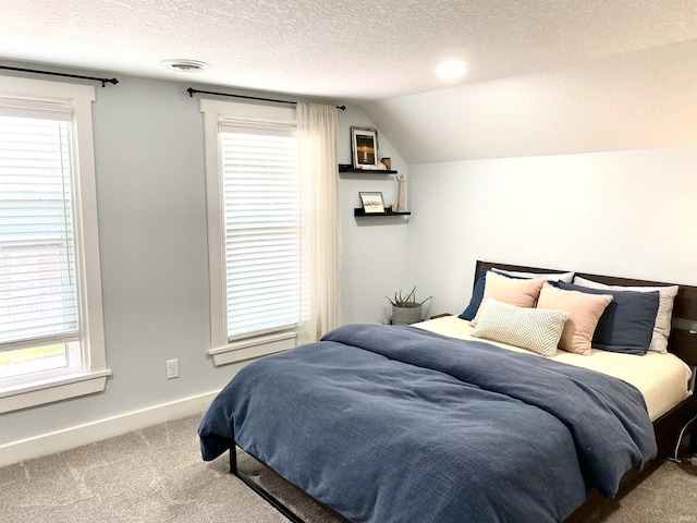 carpeted bedroom with a textured ceiling, multiple windows, baseboards, and vaulted ceiling