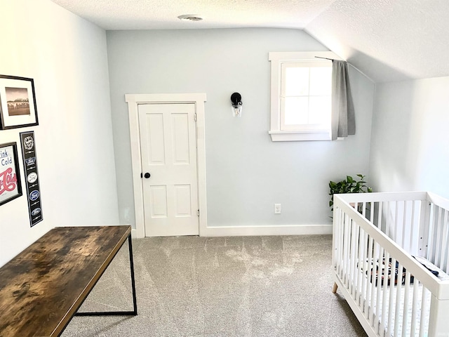 bedroom with vaulted ceiling, a textured ceiling, carpet, a crib, and baseboards