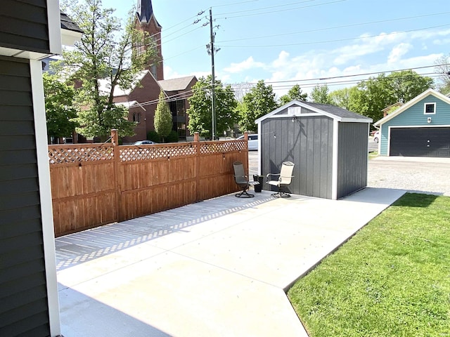 view of patio / terrace featuring an outbuilding, fence, and a storage shed
