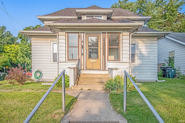 view of front of home featuring roof with shingles, a front yard, and entry steps