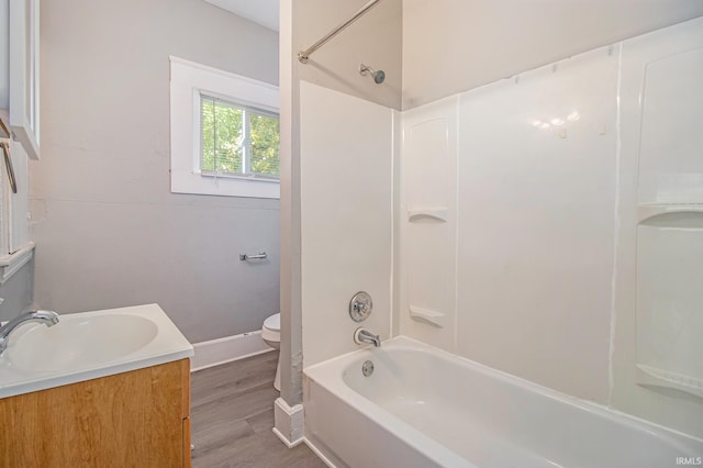 full bathroom featuring toilet, wood finished floors, baseboards, vanity, and  shower combination