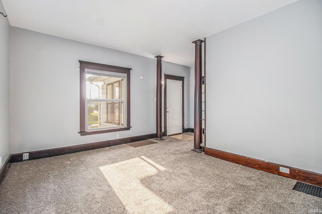 carpeted spare room with baseboards and decorative columns
