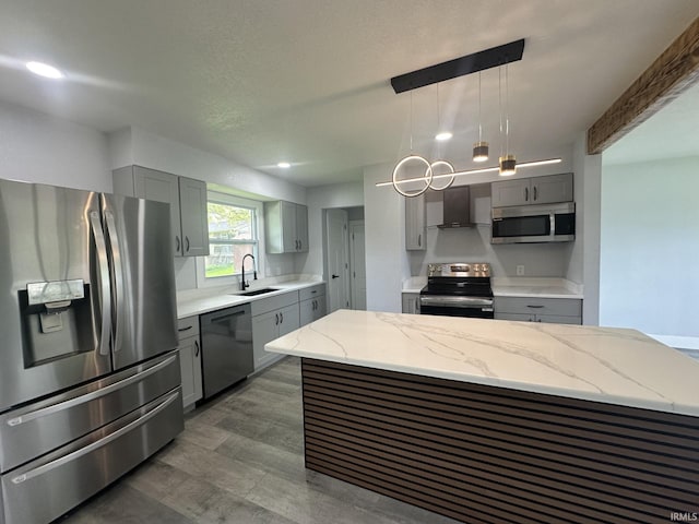916 2nd Ave, Jasper, IN 47546 - kitchen featuring appliances with stainless steel finishes, gray cabinetry, wall chimney exhaust hood, light stone counters, and a sink