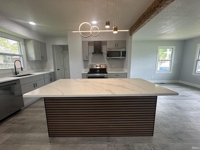916 2nd Ave, Jasper, IN 47546 - kitchen featuring gray cabinets, appliances with stainless steel finishes, a sink, wall chimney range hood, and light stone countertops