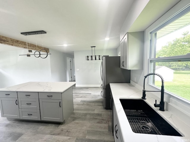 916 2nd Ave, Jasper, IN 47546 - kitchen with gray cabinetry, a sink, light stone counters, and hanging light fixtures