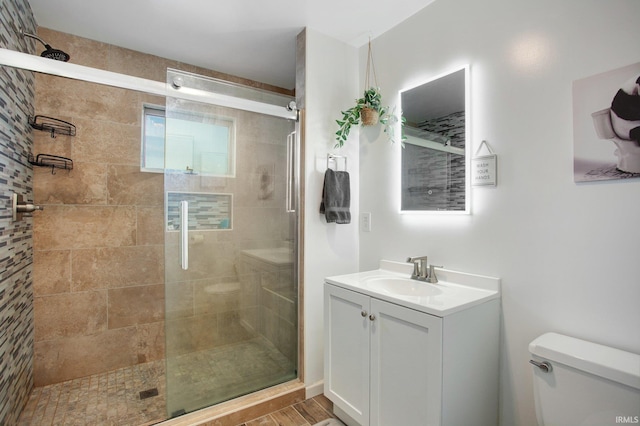 full bath with a stall shower, toilet, vanity, and wood finished floors