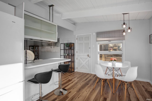 kitchen featuring beam ceiling, wood finished floors, pendant lighting, wooden ceiling, and light countertops