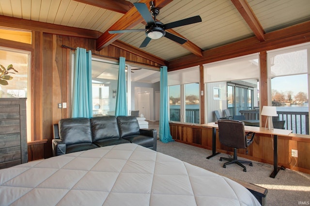 bedroom with carpet floors, an office area, wood walls, and a water view