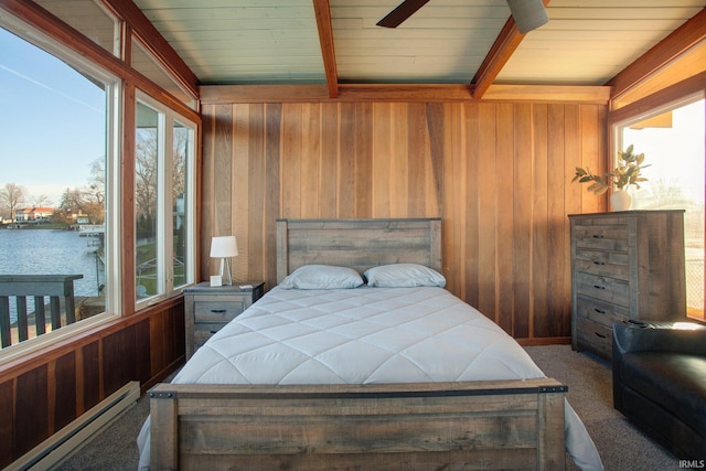 carpeted bedroom featuring baseboard heating, wood walls, multiple windows, beam ceiling, and a water view