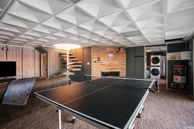 recreation room with stacked washer / drying machine, carpet, and a stone fireplace