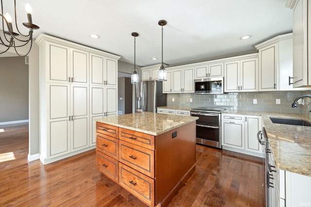 kitchen with stainless steel appliances, a sink, dark wood finished floors, backsplash, and a kitchen island