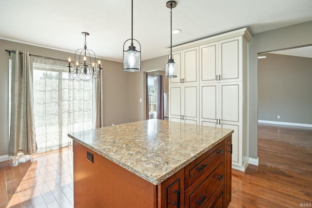 kitchen featuring wood finished floors, light stone countertops, a chandelier, baseboards, and recessed lighting