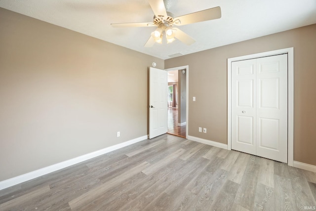 unfurnished bedroom with light wood-type flooring, baseboards, a closet, and a ceiling fan