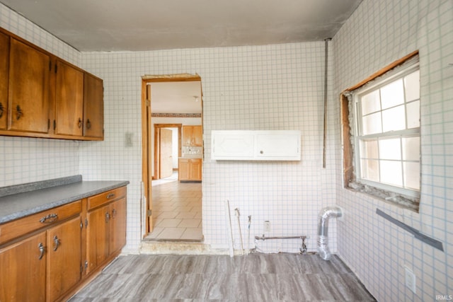 kitchen with brown cabinetry, tile walls, and light tile patterned floors