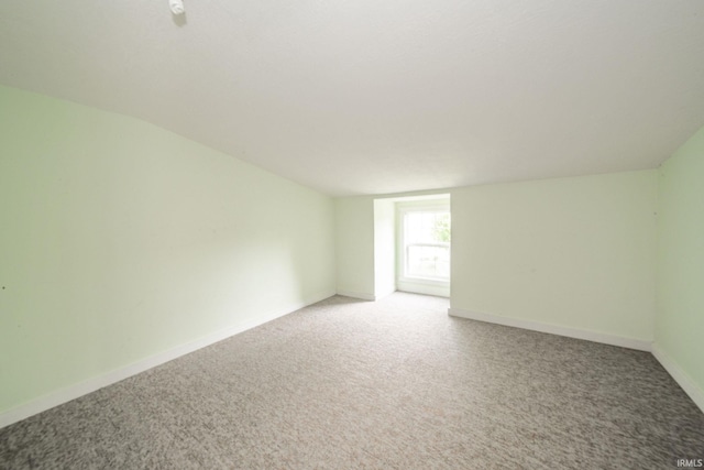 spare room featuring light colored carpet and baseboards