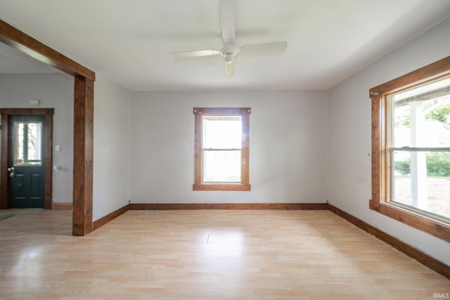 empty room with light wood-style flooring, healthy amount of natural light, and baseboards