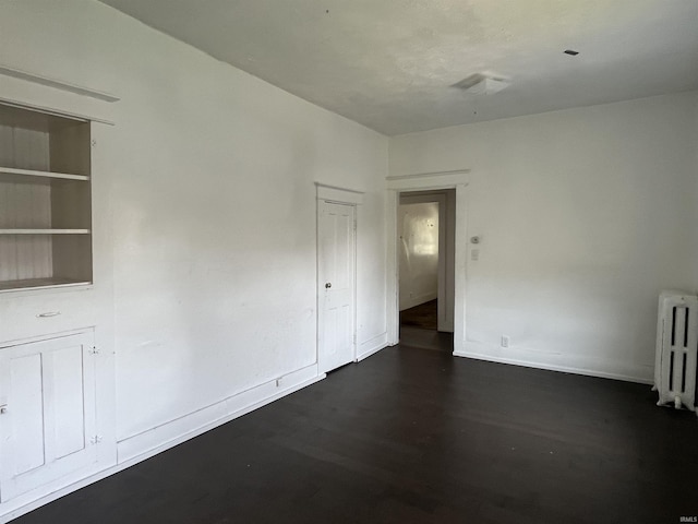 115 E 2nd St, Peru, IN 46970 - spare room featuring radiator heating unit and dark wood-style flooring