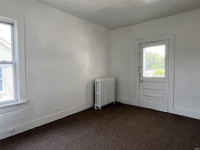 115 E 2nd St, Peru, IN 46970 - unfurnished room featuring radiator, dark carpet, and plenty of natural light