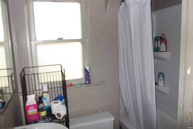 bathroom with toilet, plenty of natural light, and shower / bath combo