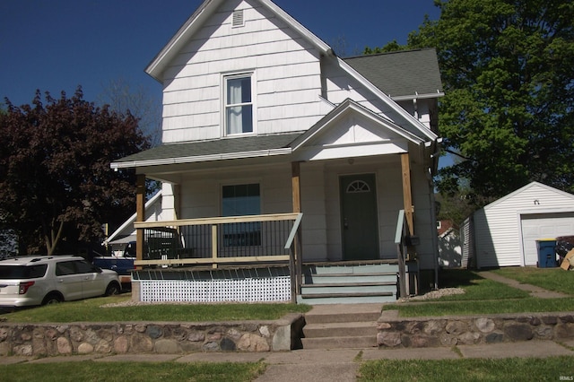 view of front of house with a porch, roof with shingles, a front lawn, and an outdoor structure