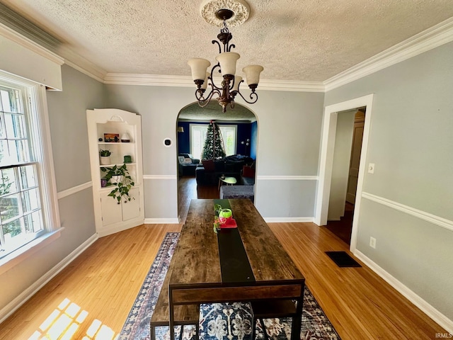 1700 W Taylor St, Kokomo, IN 46901 - dining room featuring arched walkways, a chandelier, healthy amount of natural light, wood finished floors, and a textured ceiling