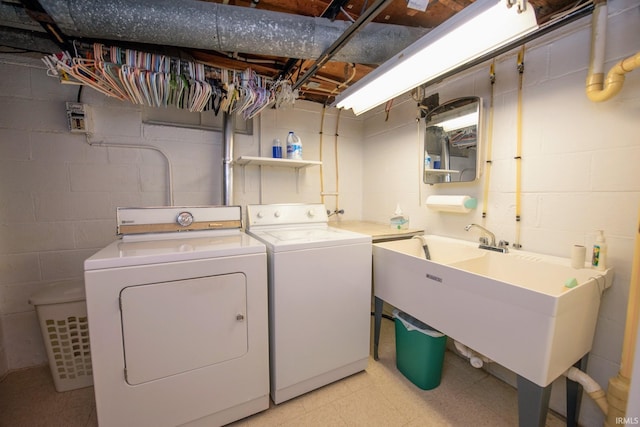 laundry room with washer and clothes dryer, light floors, and concrete block wall
