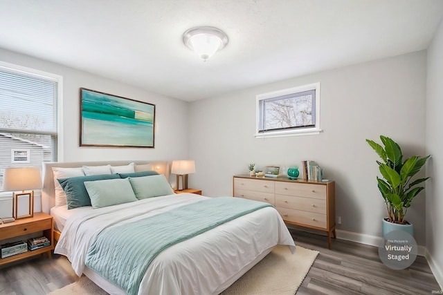 bedroom with multiple windows, wood finished floors, and baseboards
