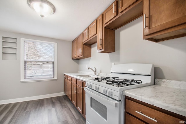 kitchen with gas range gas stove, brown cabinets, dark wood-style floors, and light countertops