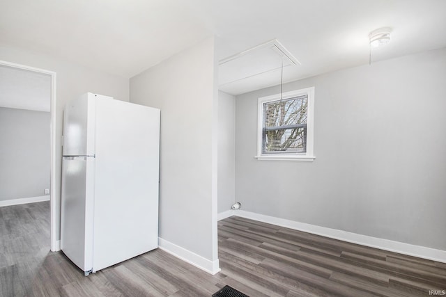 unfurnished dining area featuring attic access, wood finished floors, and baseboards