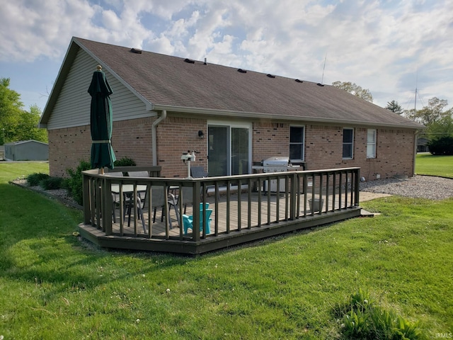 back of house with brick siding, a deck, and a lawn