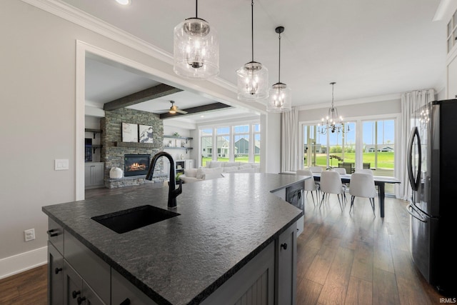 18015 Tullymore Ln, Leo, IN 46765 - kitchen with freestanding refrigerator, a sink, a stone fireplace, ceiling fan, and dark wood-style flooring