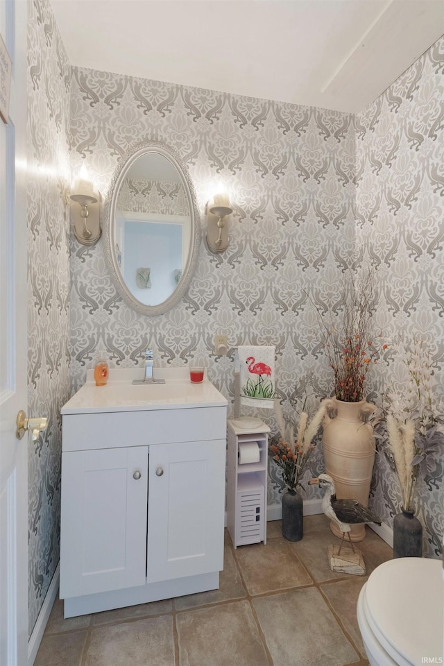 bathroom featuring wallpapered walls, toilet, baseboards, vanity, and tile patterned flooring