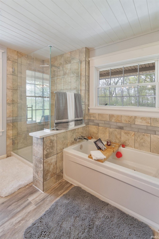 bathroom with wood finished floors, a bath, a shower stall, and wooden ceiling